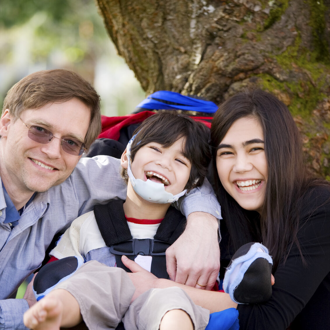Boy with cerebral palsy in wheelchair surrounded by family