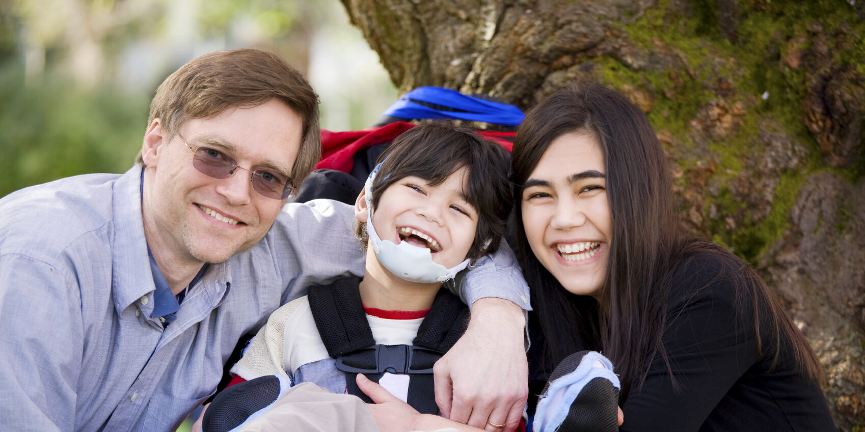 Boy with cerebral palsy in wheelchair surrounded by family